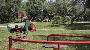 A playground with various equipment including swings, slides, and a seesaw.