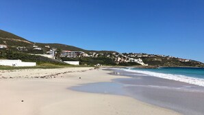 A beach with a clear sky, sandy shore, and buildings in the background. - The Waves; Oceanfront 2 Bedroom. Gorgeous Sunrises. Relax With The Wave Rythyms (Philipsburg)
