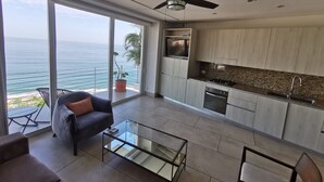 Uma cozinha moderna com vista para o oceano, um ventilador de teto e uma mesa de centro de vidro.