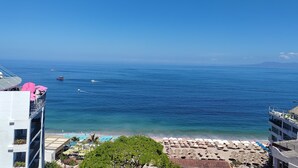 Um hotel à beira-mar com vista para o oceano, área de piscina e guarda-sóis de praia.