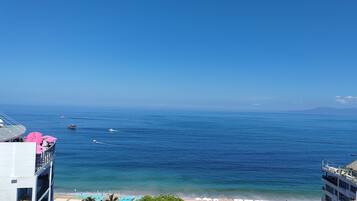 Um hotel à beira-mar com vista para o oceano, área de piscina e guarda-sóis de praia.