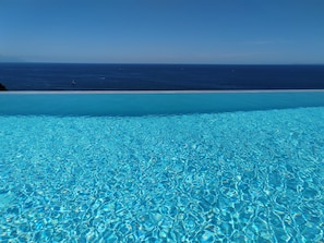 Ein klares, blaues Schwimmbecken mit Blick auf den Ozean und einen Sandstrand.