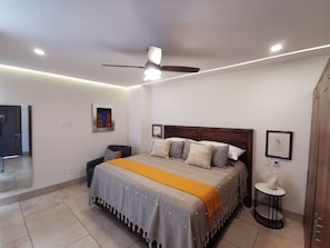 Ein modernes Schlafzimmer mit Bett, Deckenventilator und Nachttisch.