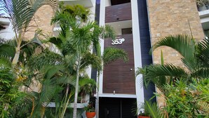 Um edifício moderno com fachada de pedra, grandes vasos de plantas e céu limpo.