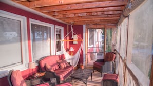 Un espace extérieur accueillant, aménagé avec des meubles en osier, un hamac et une table avec une lampe.