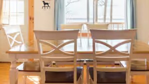 Un coin repas avec une table en bois et des chaises blanches.