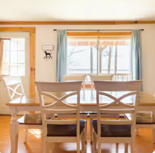 Un coin repas avec une table en bois et des chaises blanches.