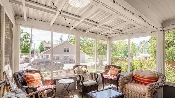 A covered porch with wicker furniture, a glass table, and large windows offering views of a residential area. - Family Fun & Sun in Bolton - walking distance to town, beaches, & lake (Bolton)