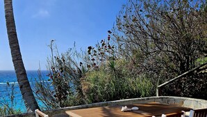 A wooden table and chairs set outdoors with a view of the ocean.
