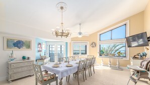 A dining area with a table set for six, a chandelier, and a television on a stand.