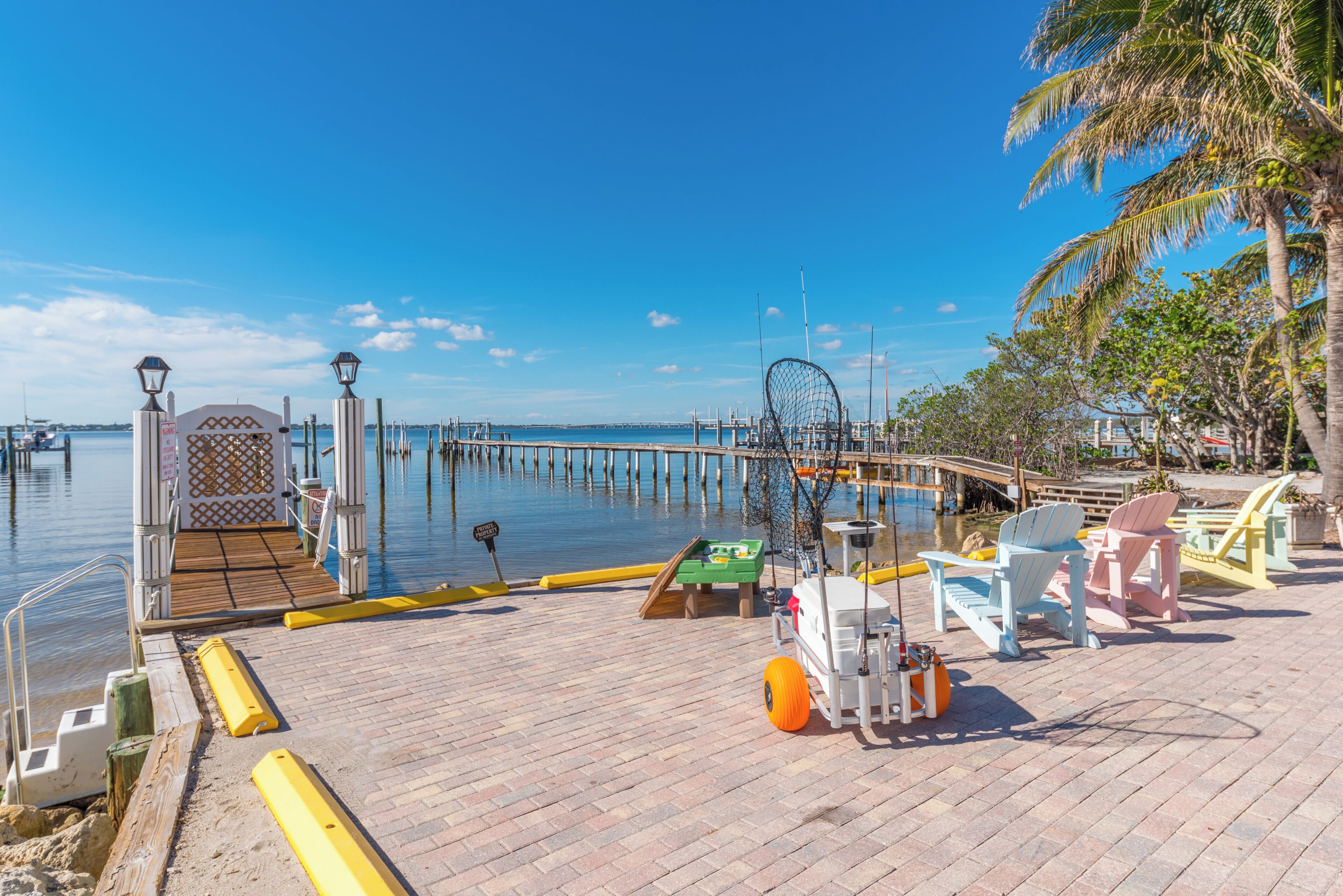 Un muelle con pasarela de madera, equipo de pesca y sillas.