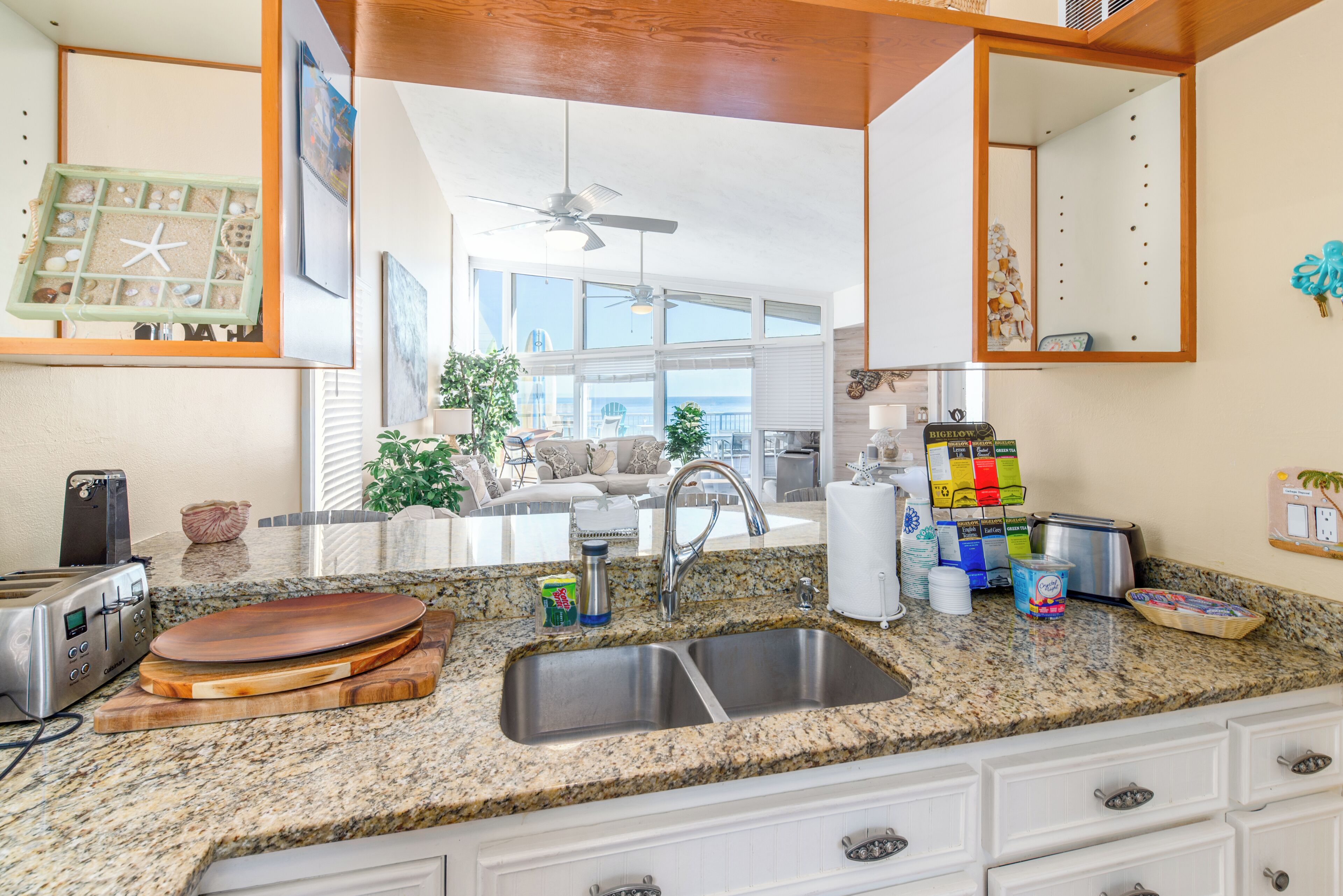 A kitchen with granite countertops, a built-in sink, and a dining area with a view of the ocean.
