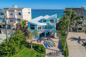 A coastal property with a prominent blue building, a paved walkway, and several kayaks and bicycles.