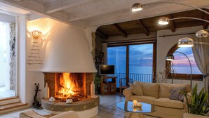 Un salon chaleureux avec une cheminée, des fauteuils confortables et une vue sur la mer.