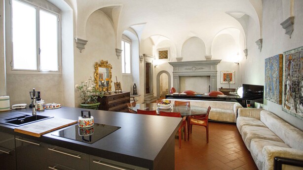 A spacious kitchen with a central island, a dining area with a sofa and chairs, and a fireplace. - Luxury Renaissance Palace (Firenze)