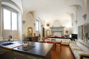 A spacious kitchen with a central island, a dining area with a sofa and chairs, and a fireplace. - Luxury Renaissance Palace (Firenze)