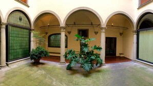 A courtyard with arches, a potted plant, and a tiled floor. - Luxury Renaissance Palace (Firenze)