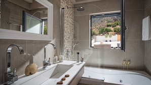 A modern bathroom with a double sink, a large mirror, a shower, and a bathtub.