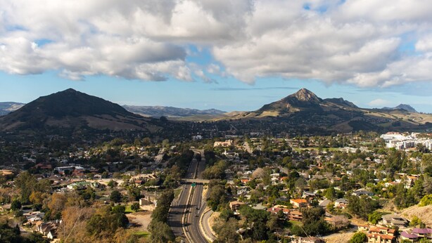 A town with a prominent mountain in the background, a highway, and residential areas.
