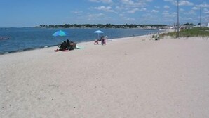 A beach with a sandy shore, a few umbrellas, and a calm sea. - Wonderful location, walk to beach, private yard, Voted #1 in town by AB&B (old saybrook)