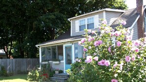 A house with a front porch, a small garden with pink flowers, and a white picket fence. - Wonderful location, walk to beach, private yard, Voted #1 in town by AB&B (old saybrook)
