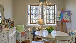 A dining area with a round table, white chairs, a bowl of fruit, and a painting on the wall. - Wonderful location, walk to beach, private yard, Voted #1 in town by AB&B (old saybrook)
