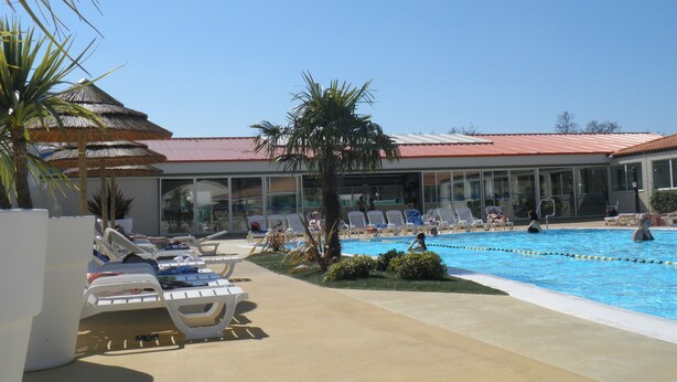 A pool area with lounge chairs and a palm tree. - Spacious, comfortable mobile home for 6/8 people (40m2) (Les Mathes)