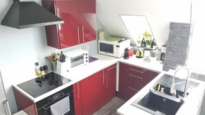 Une cuisine de taille réduite avec des placards rouges, un four à micro-ondes, un grille-pain et un évier.
