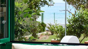 A view from a window with a metal showerhead, a green-framed window, and a cushion with a floral pattern. - Beach Villa in Crete - Villa Kirvas (Ierapetra)