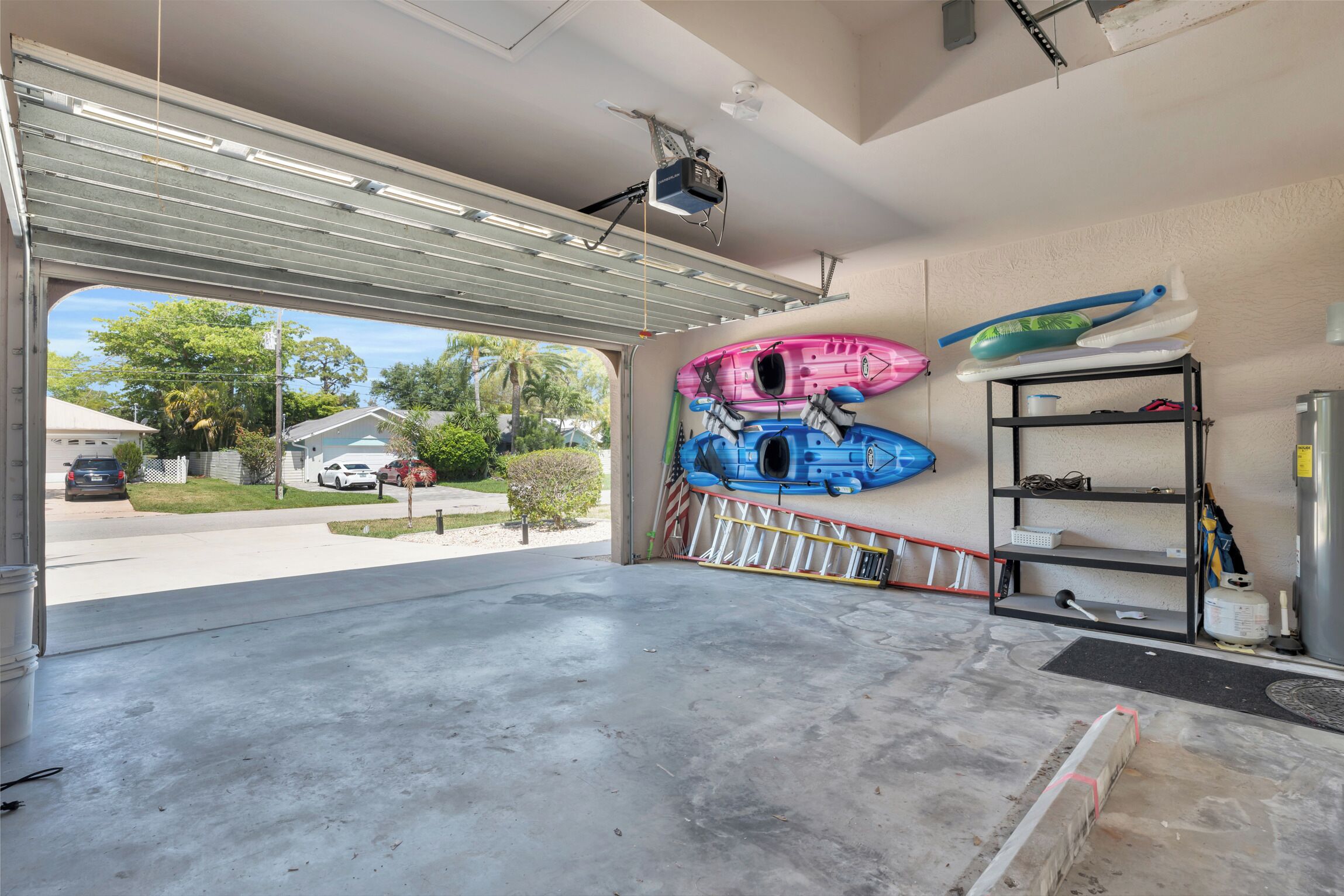 A garage with a large opening, a ceiling-mounted projector, and kayaks on the wall.