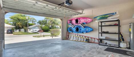 A garage with a large opening, a ceiling-mounted projector, and kayaks on the wall.