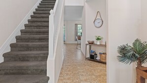A staircase leading to a second floor with a white railing, a clock on the wall, and a potted plant on the landing. - Waterfront! Boat dock available for rent, pet friendly, families welcome!  (Homosassa)