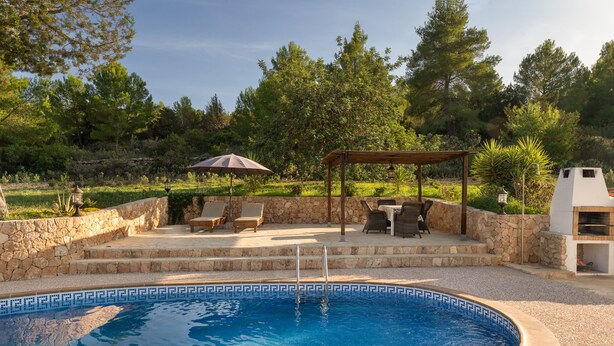 Ein Pool mit Steinveranda, überdachter Sitzecke und Grill.