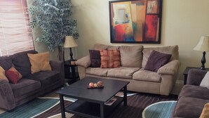 A living room with two sofas, a coffee table, and a large abstract painting on the wall. - Disney Quiet, Spacious, Contemporary / Salt Water Pool & Spa, Wi-fi (Davenport)