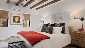 A bedroom with a bed, bedside table, lamp, and a window with blinds. - Kiva Fireplace, Peaceful Luxury, Walk Everywhere (Santa Fe)