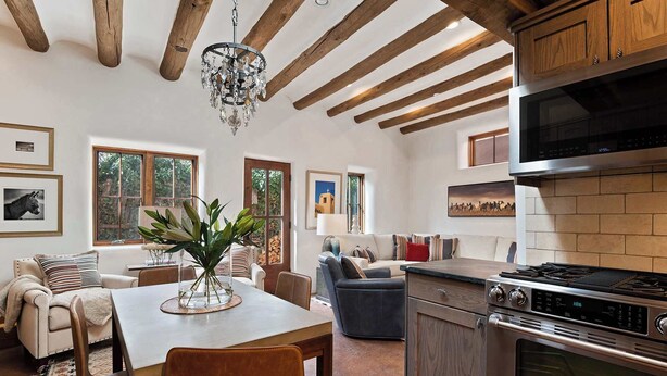 A modern kitchen with a stainless steel stove, wooden beams, and a chandelier. - Kiva Fireplace, Peaceful Luxury, Walk Everywhere (Santa Fe)