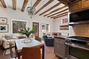 Una cocina moderna con estufa de acero inoxidable, vigas de madera y una araña.