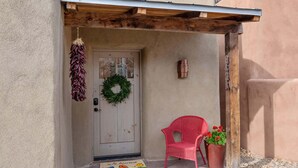 A door with a wreath, a red chair, and a welcome mat. - Kiva Fireplace, Peaceful Luxury, Walk Everywhere (Santa Fe)