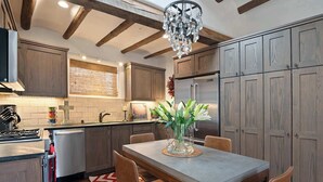 A kitchen with wooden cabinets, a dining table with chairs, a chandelier, and a refrigerator. - Kiva Fireplace, Peaceful Luxury, Walk Everywhere (Santa Fe)