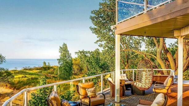 A covered outdoor seating area with wicker furniture and a view of the sea. - Skyline Views, Hot Tub, Beachfront, Lavish Kitchen at Dunetop Villa (Miller Beach)