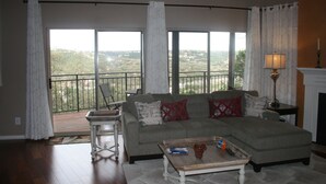 Een woonkamer met een bank, een salontafel en uitzicht op een balkon met een hekwerk.
