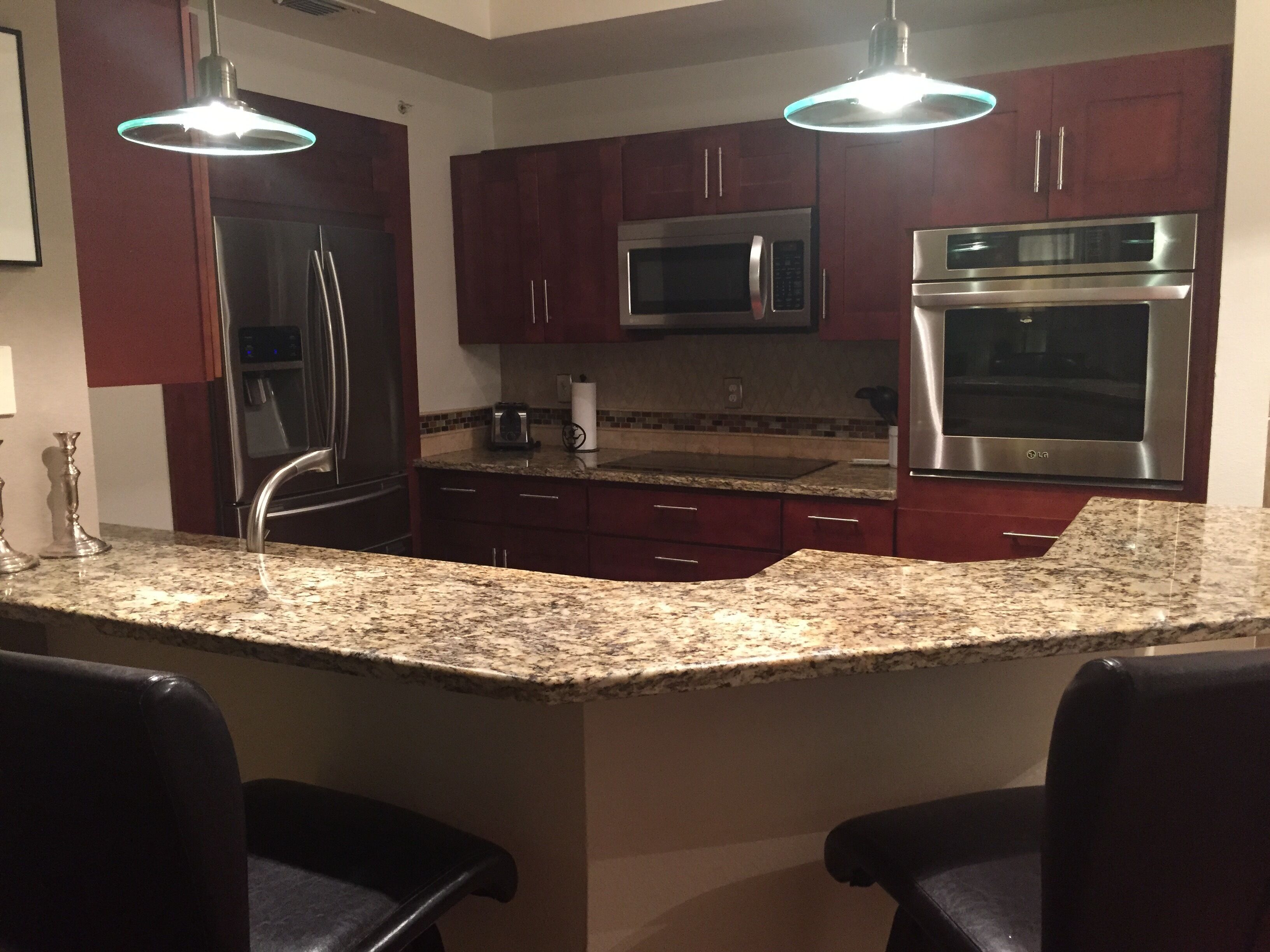 A kitchen with granite countertops, stainless steel appliances, and dark wooden cabinets.