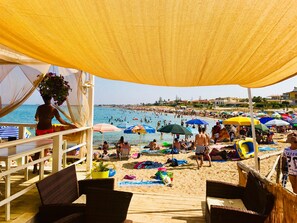 Une plage avec des parasols, des gens et une jetée.