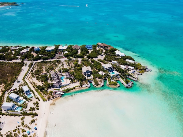 An aerial view of a coastal resort with multiple buildings, a beach, and clear turquoise waters. - Oceanfront Villa - Private Dock for Snorkeling, 3 mins to Private Beach (Providenciales)