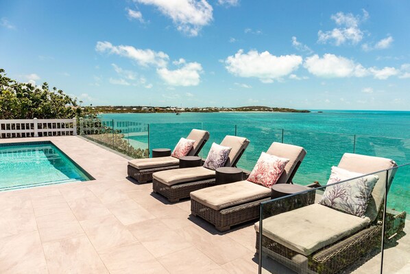 A poolside area with lounge chairs and a clear view of the ocean. - Oceanfront Villa - Private Dock for Snorkeling, 3 mins to Private Beach (Providenciales)