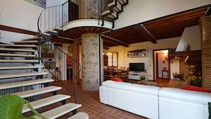 Ein geräumiger Wohnbereich mit einem weißen Sofa, einem Esstisch und einer Wendeltreppe.