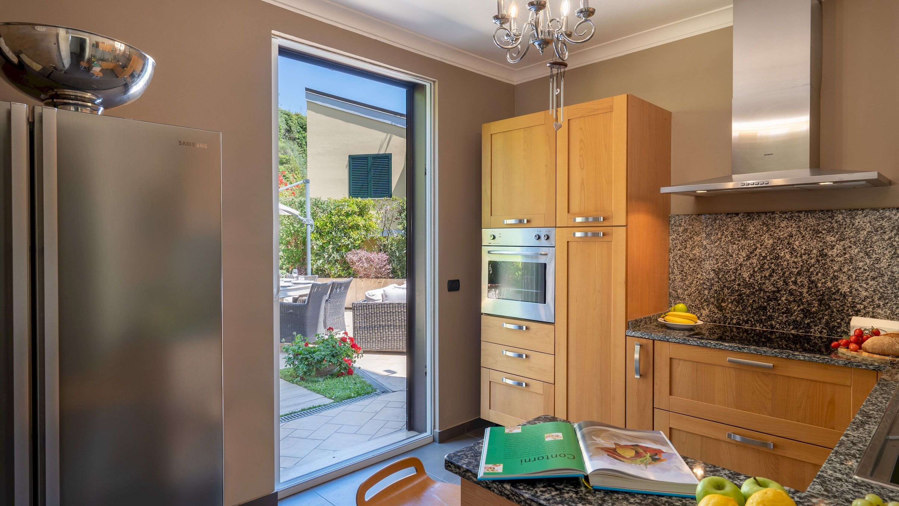 Cocina moderna con armarios de madera, un refrigerador de acero inoxidable y una encimera de granito.