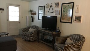 Una sala de estar con dos sillones estampados, un televisor y una mesita.