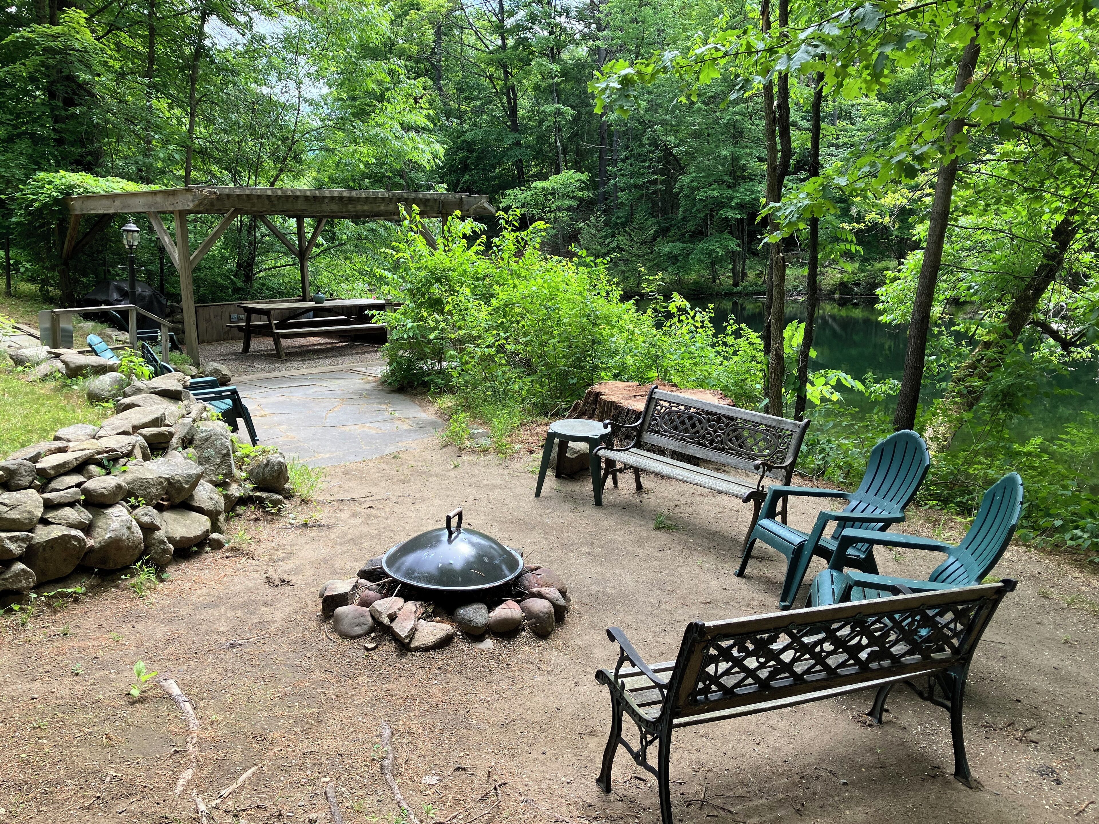 An outdoor patio area with a fire pit, seating, and a wooden pergola.