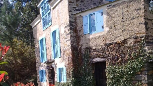 Un edifici de pedra amb persianes blaves i una petita porta d'entrada.